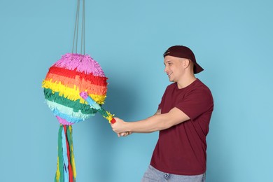 Photo of Happy man breaking pinata on light blue background