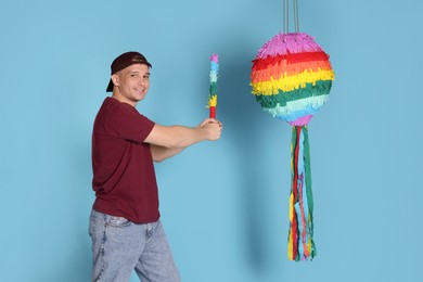 Photo of Happy man breaking pinata on light blue background