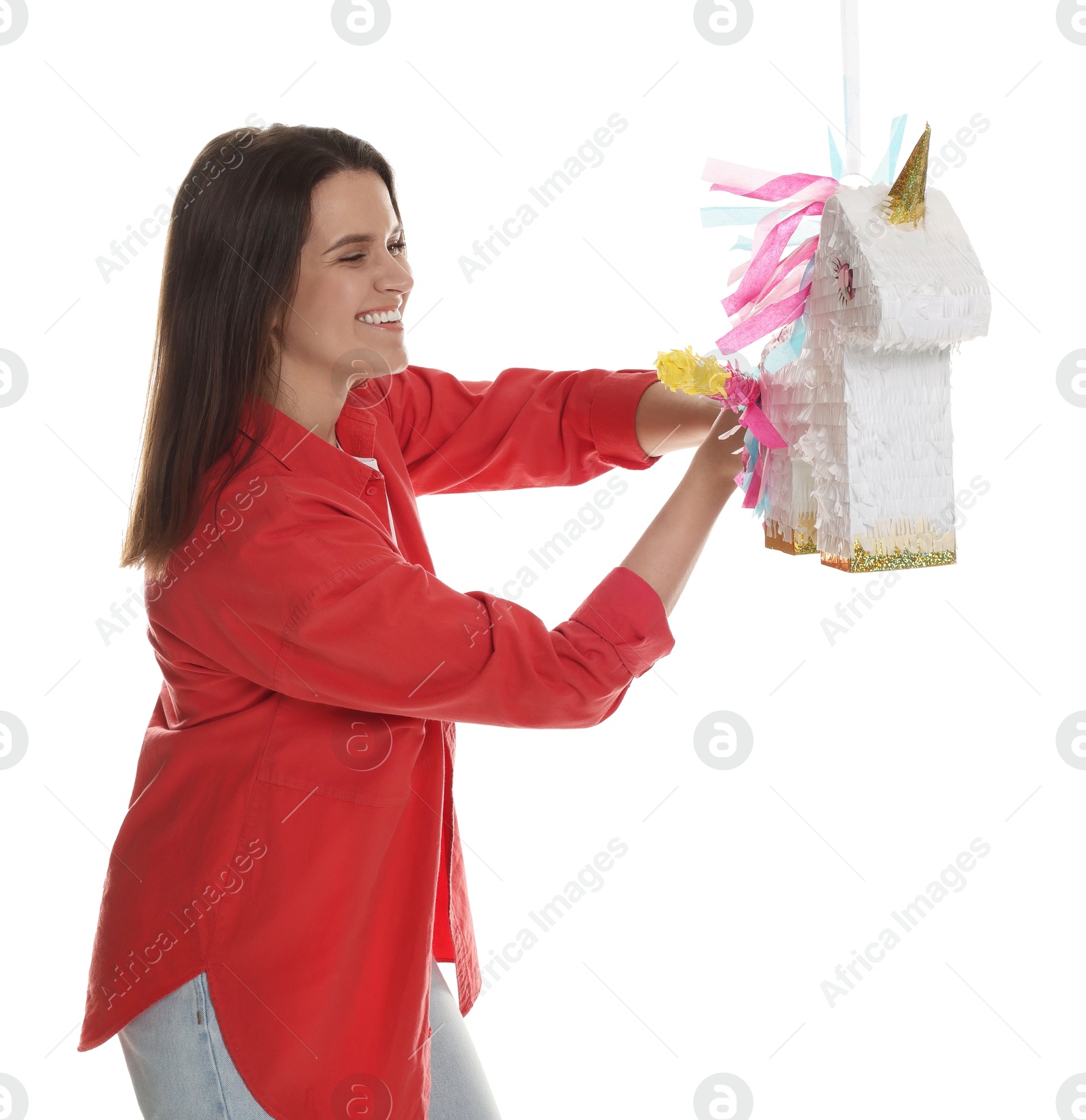 Photo of Happy woman hitting unicorn shaped pinata with stick on white background