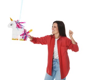 Photo of Happy woman hitting unicorn shaped pinata with stick on white background