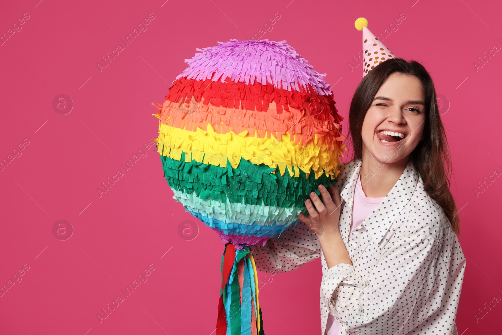 Photo of Emotional woman with colorful pinata on pink background, space for text