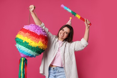 Photo of Happy woman with colorful pinata and stick on pink background