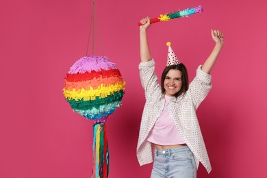 Photo of Happy woman with colorful pinata and stick on pink background