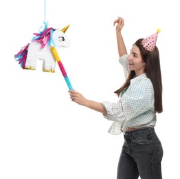 Happy woman hitting unicorn shaped pinata with stick on white background