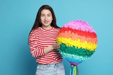 Photo of Happy woman with pinata on light blue background