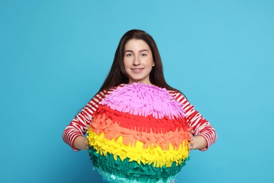 Photo of Happy woman with pinata on light blue background