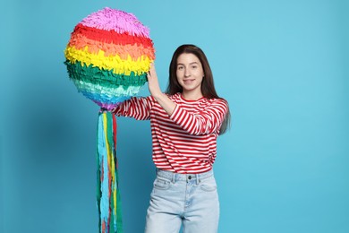 Photo of Happy woman with pinata on light blue background