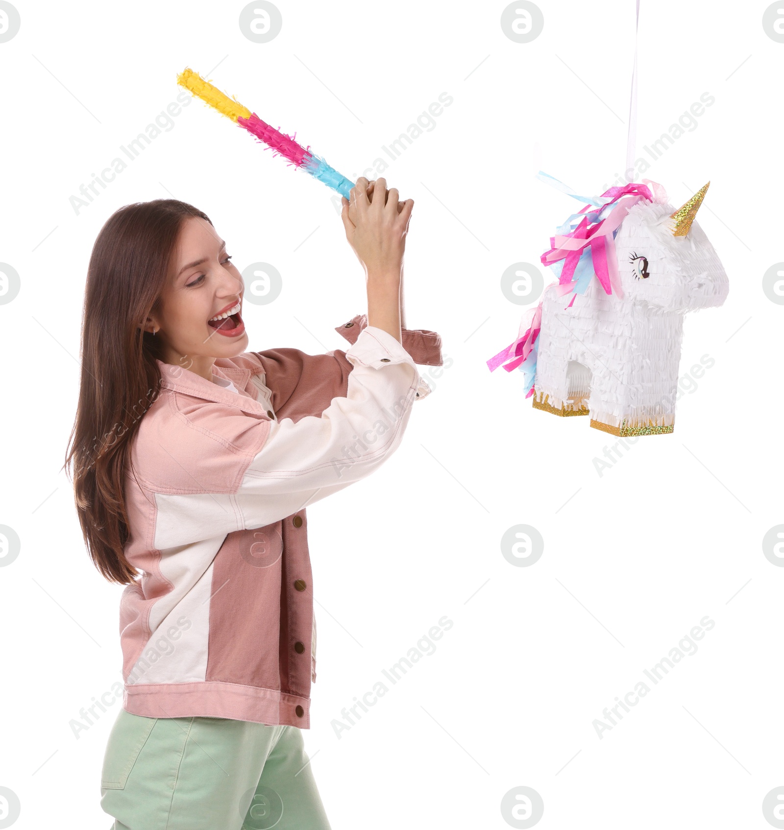 Photo of Happy woman breaking unicorn shaped pinata with stick isolated on white