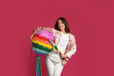 Photo of Happy woman with colorful pinata and stick on pink background