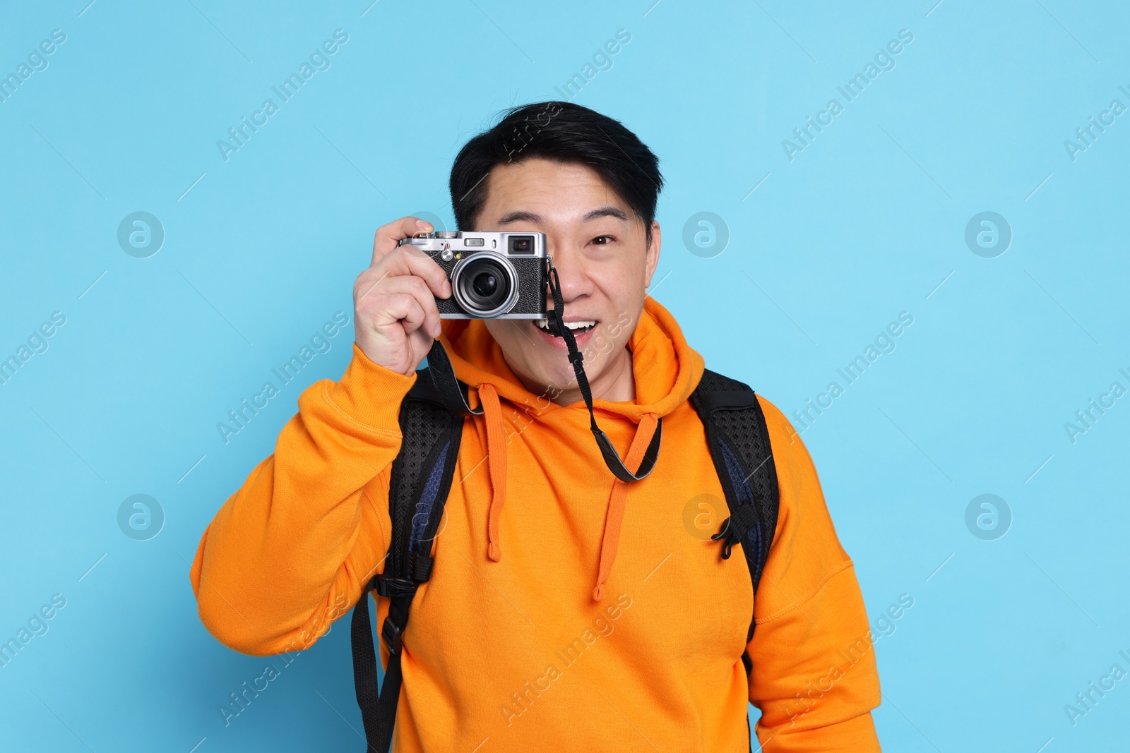 Photo of Traveller taking photo on light blue background