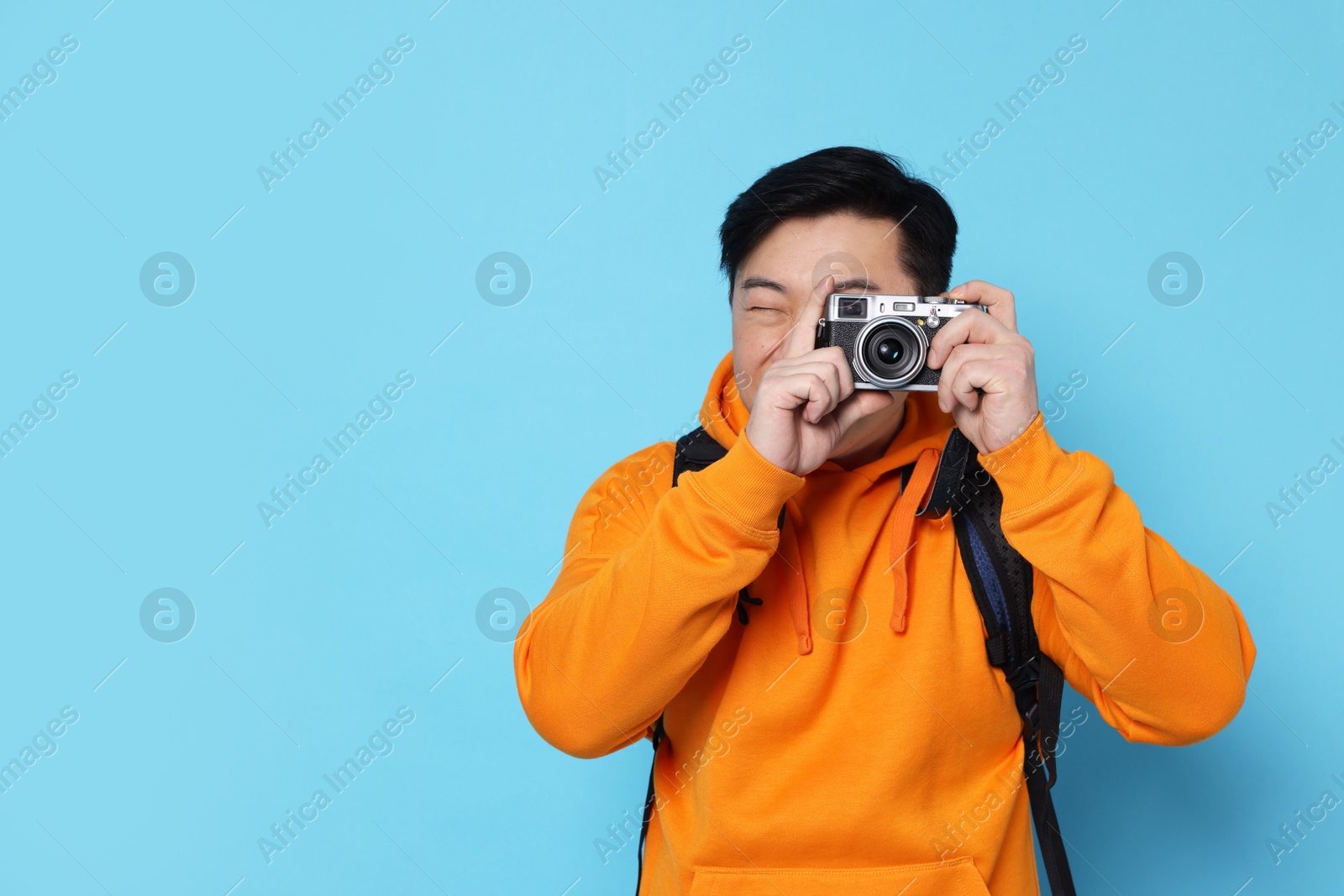 Photo of Traveller taking photo on light blue background. Space for text