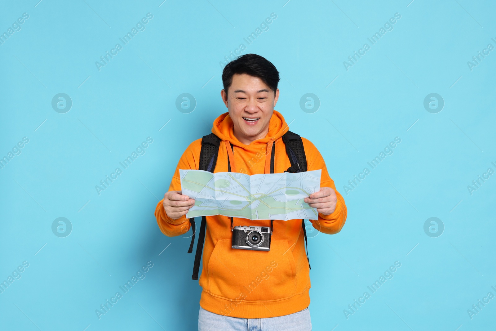 Photo of Happy traveller with map on light blue background