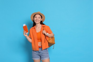 Photo of Happy traveller with backpack and passport on light blue background. Space for text