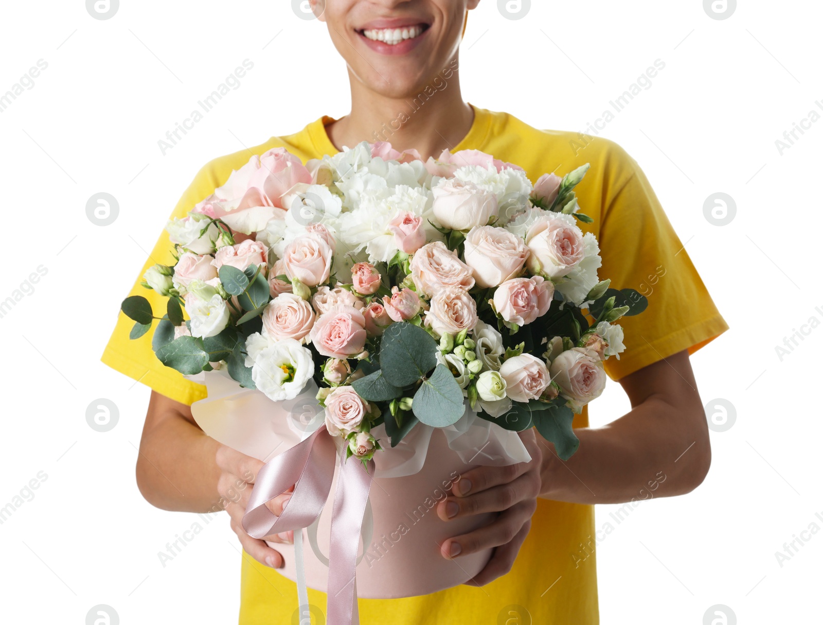 Photo of Smiling delivery man holding gift box with beautiful floral composition on white background, closeup