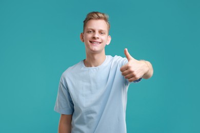 Photo of Happy man showing thumbs up on light blue background. Like gesture