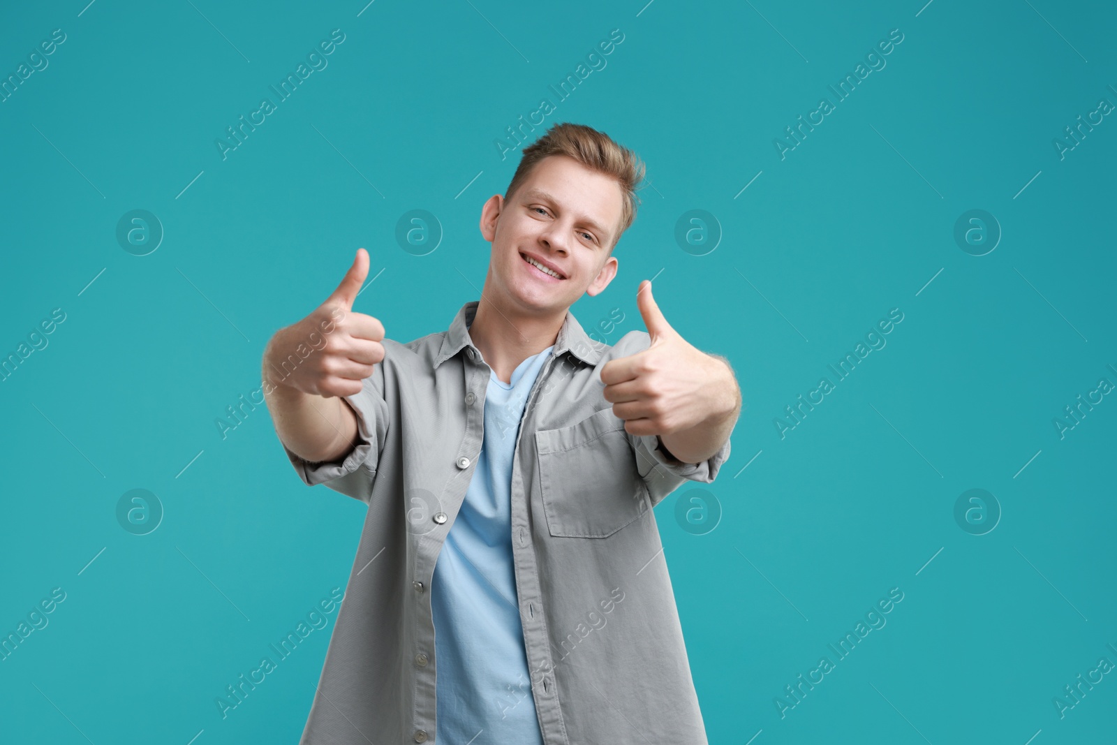 Photo of Happy man showing thumbs up on light blue background. Like gesture