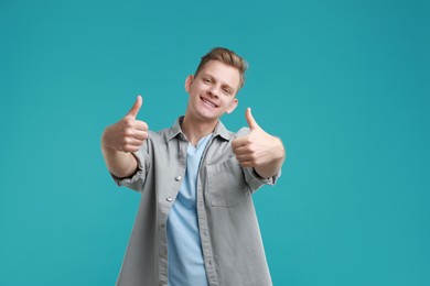 Photo of Happy man showing thumbs up on light blue background. Like gesture