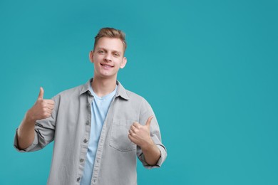 Photo of Happy man showing thumbs up on light blue background, space for text. Like gesture