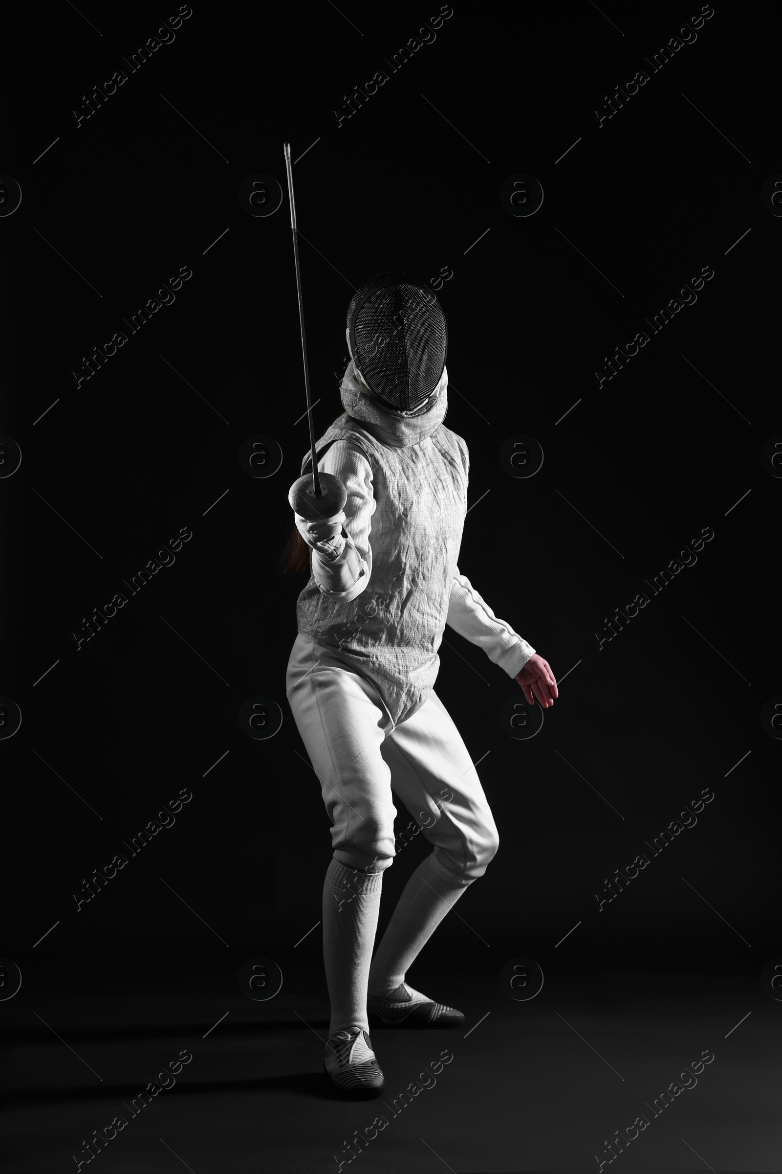 Photo of Fencer with epee practicing on dark background