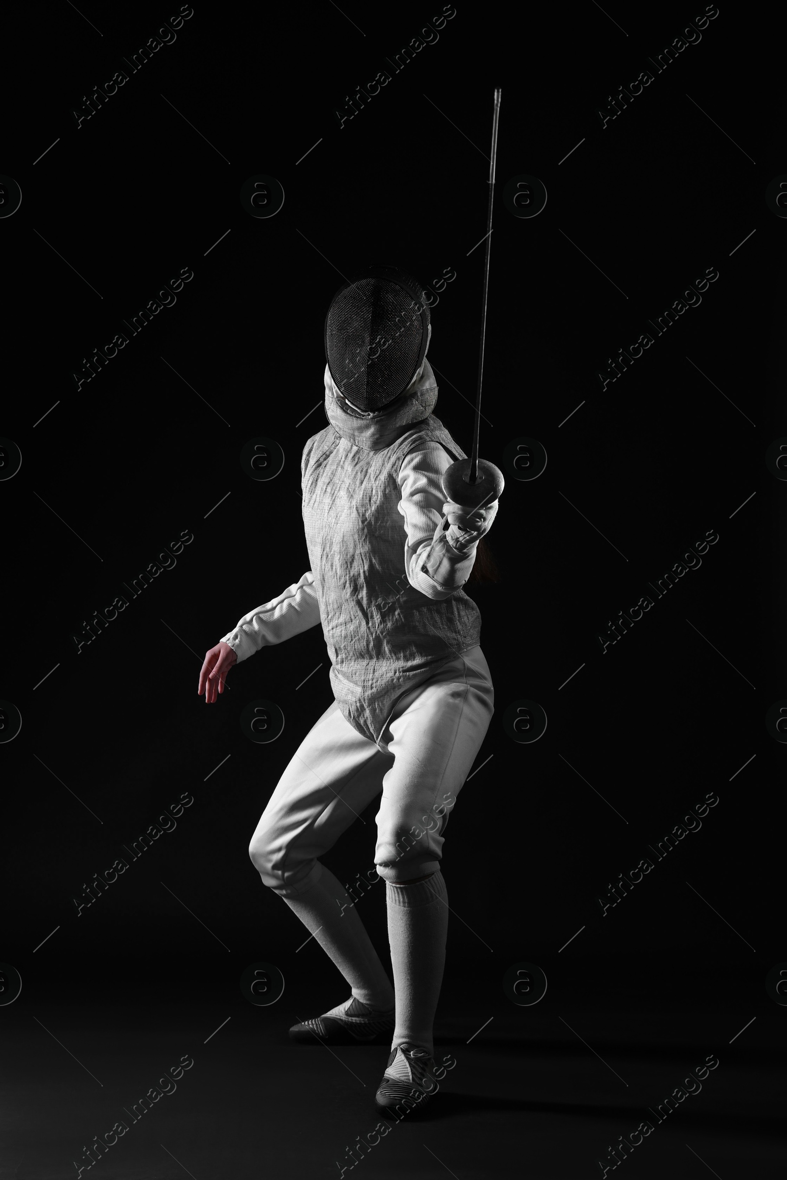 Photo of Fencer with epee practicing on dark background