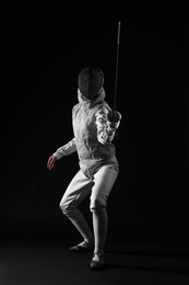 Photo of Fencer with epee practicing on dark background