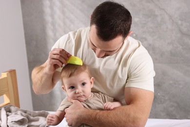 Photo of Man brushing hair of his little baby on bed indoors