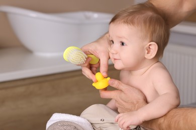 Photo of Man brushing hair of his little baby indoors, closeup. Space for text