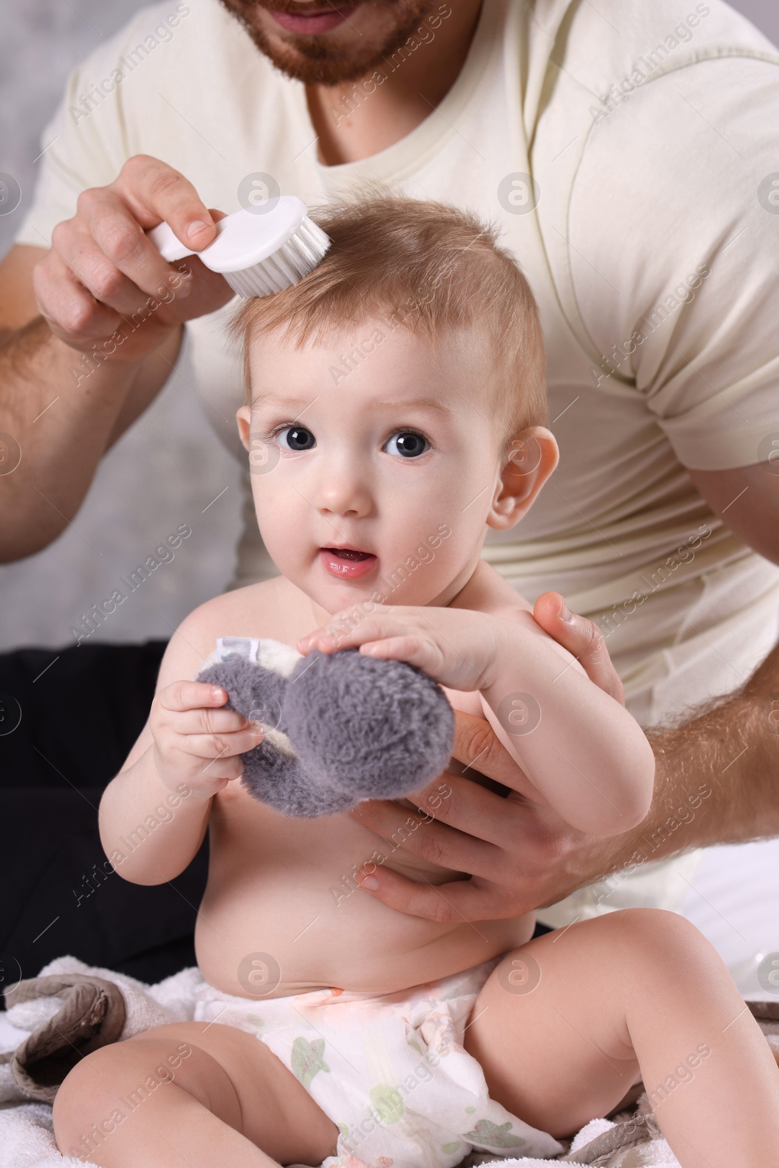 Photo of Man brushing hair of his little baby indoors, closeup