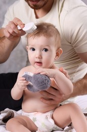 Man brushing hair of his little baby indoors, closeup