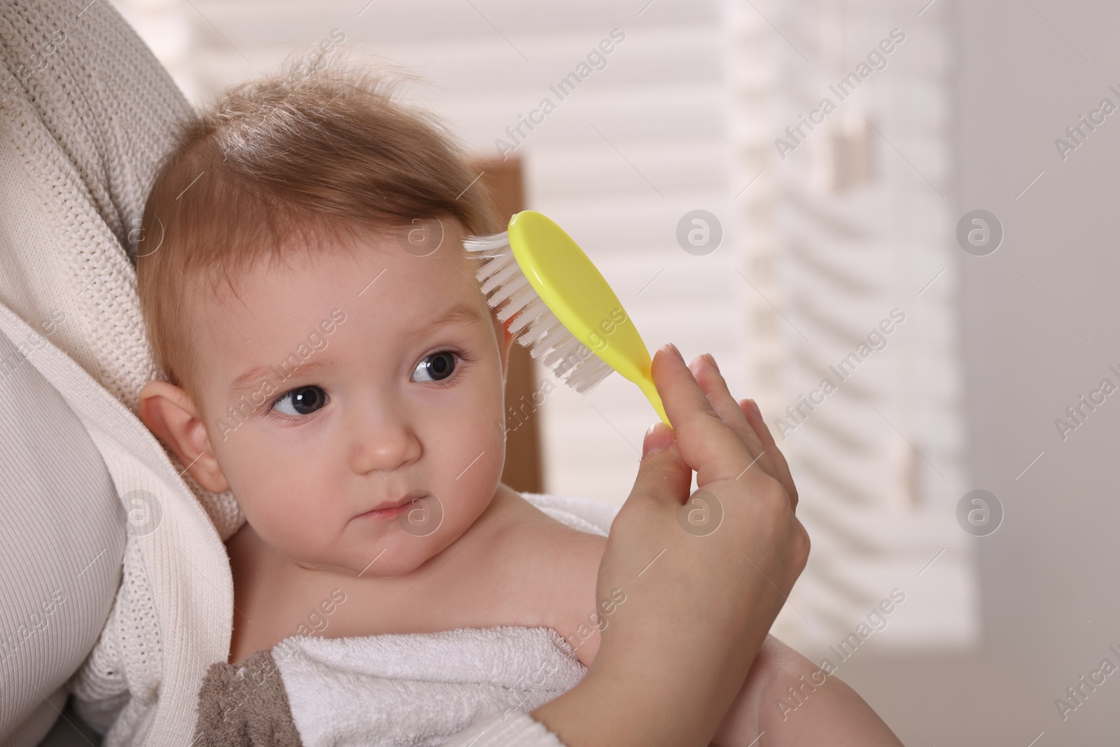 Photo of Woman brushing hair of her little baby indoors, closeup. Space for text