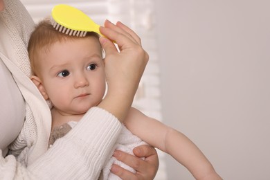 Photo of Woman brushing hair of her little baby indoors, closeup. Space for text