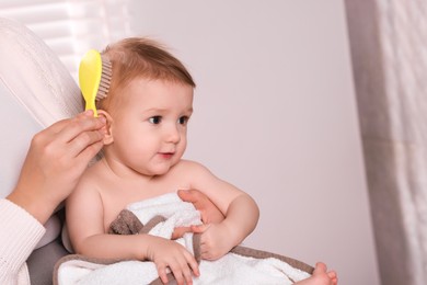 Photo of Woman brushing hair of her little baby indoors, closeup. Space for text