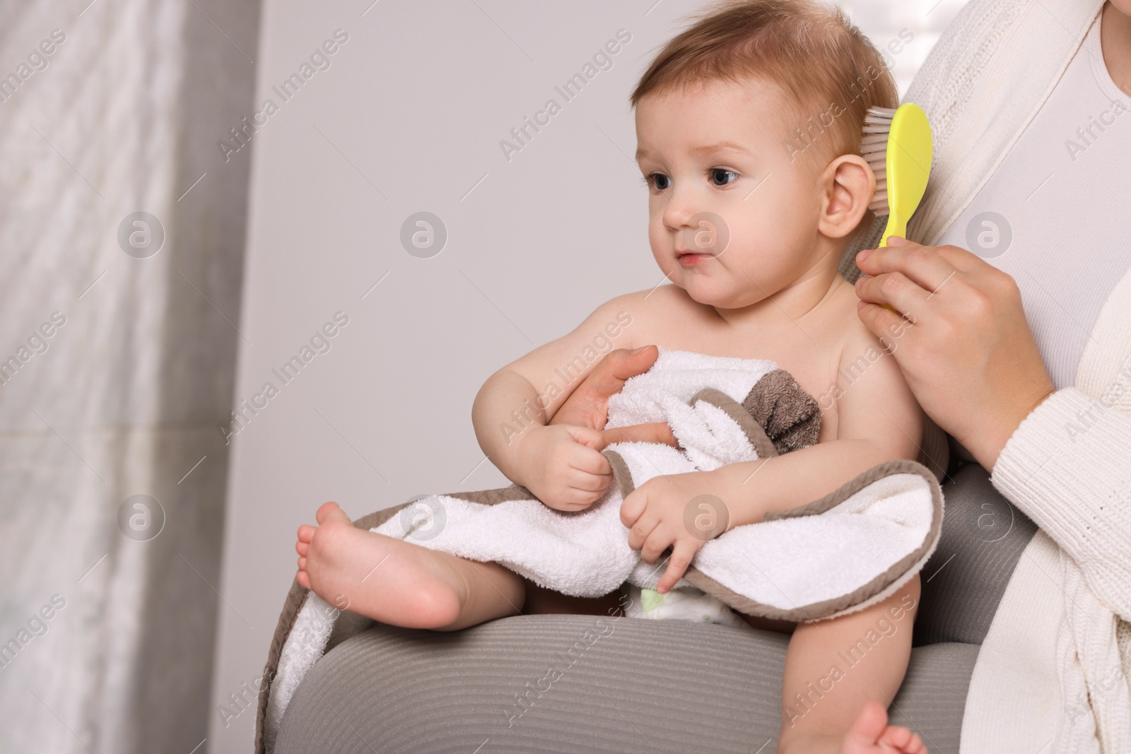 Photo of Woman brushing hair of her little baby indoors, closeup. Space for text