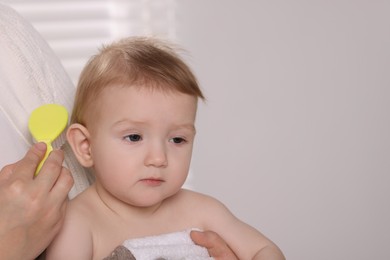 Photo of Woman brushing hair of her little baby indoors, closeup. Space for text