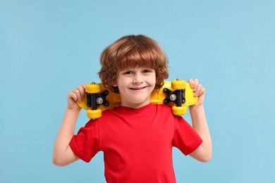 Photo of Little boy with penny board on light blue background