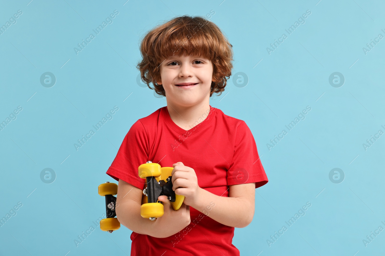 Photo of Little boy with penny board on light blue background