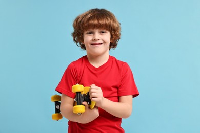 Photo of Little boy with penny board on light blue background