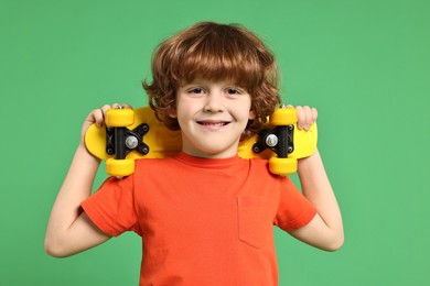 Little boy with penny board on light green background