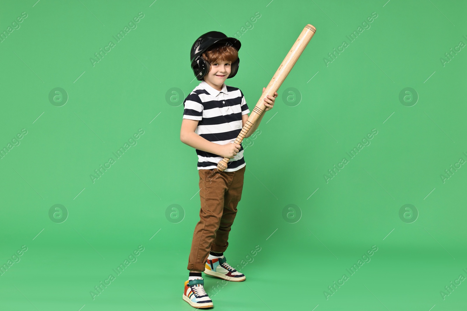 Photo of Little boy in helmet with baseball bat on light green background