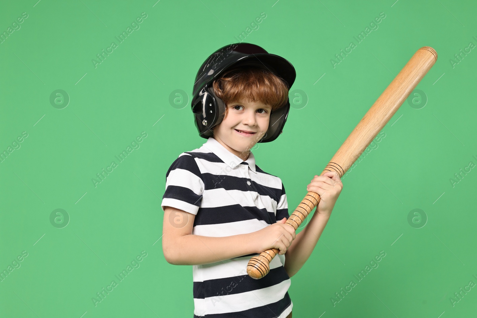 Photo of Little boy in helmet with baseball bat on light green background