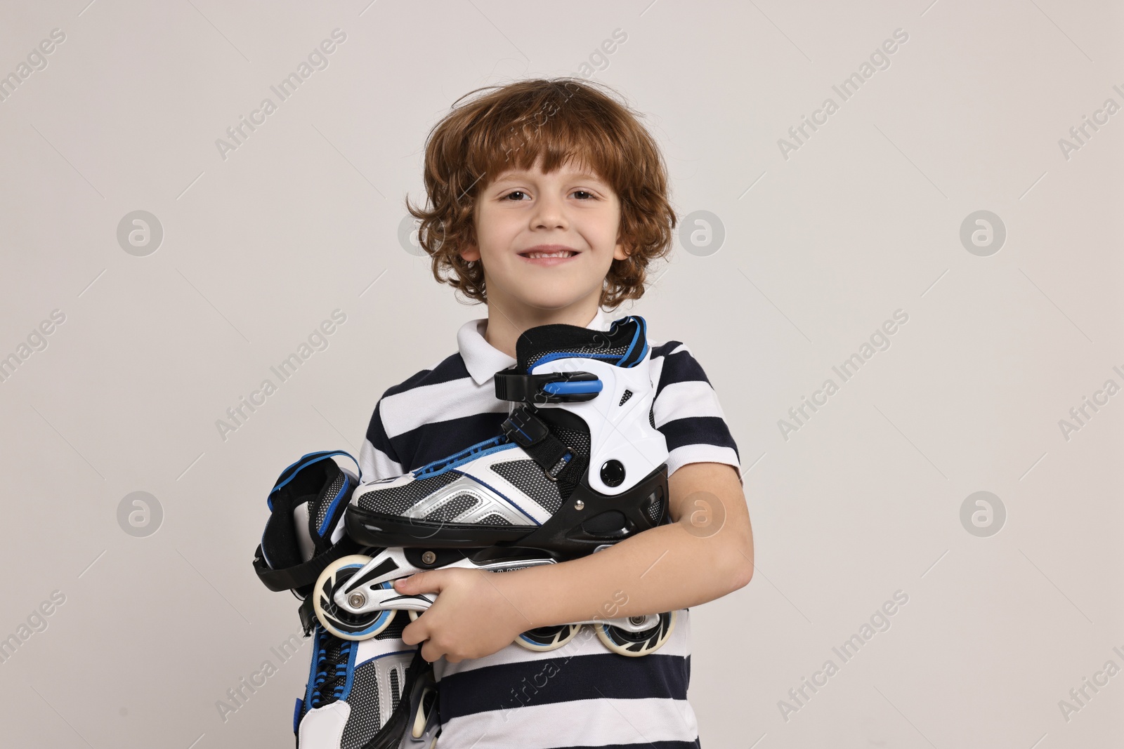 Photo of Little boy with roller skates on light grey background