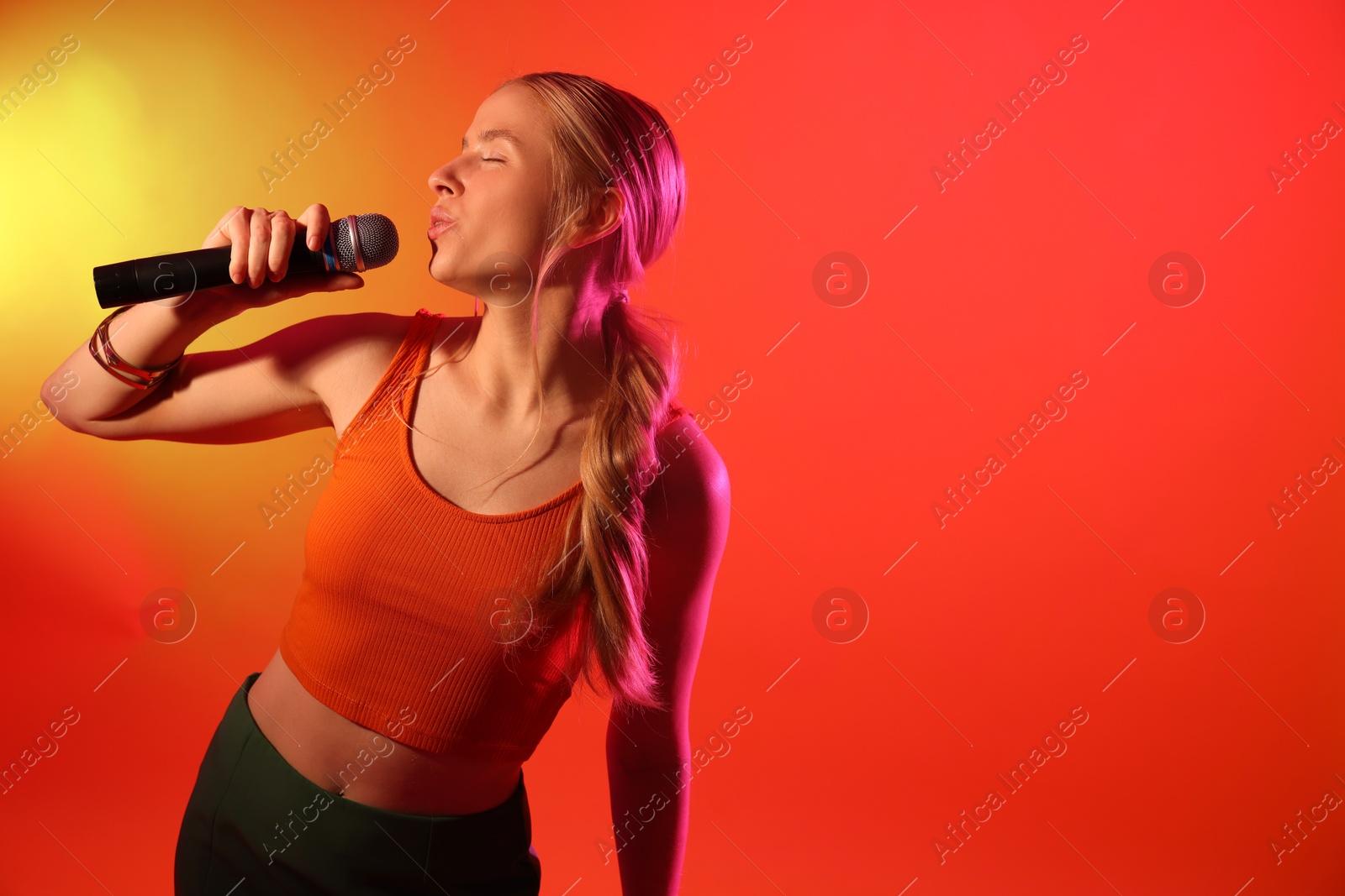 Photo of Talented singer performing on red background with yellow light. Space for text