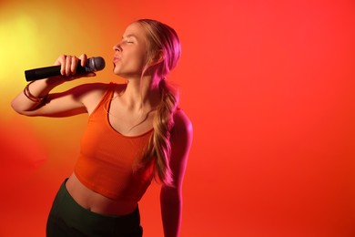 Photo of Talented singer performing on red background with yellow light. Space for text