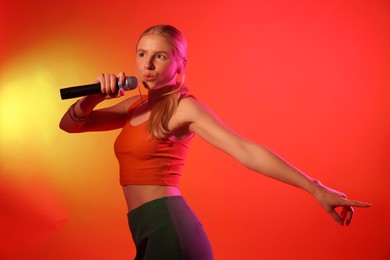 Photo of Talented singer performing on red background with yellow light