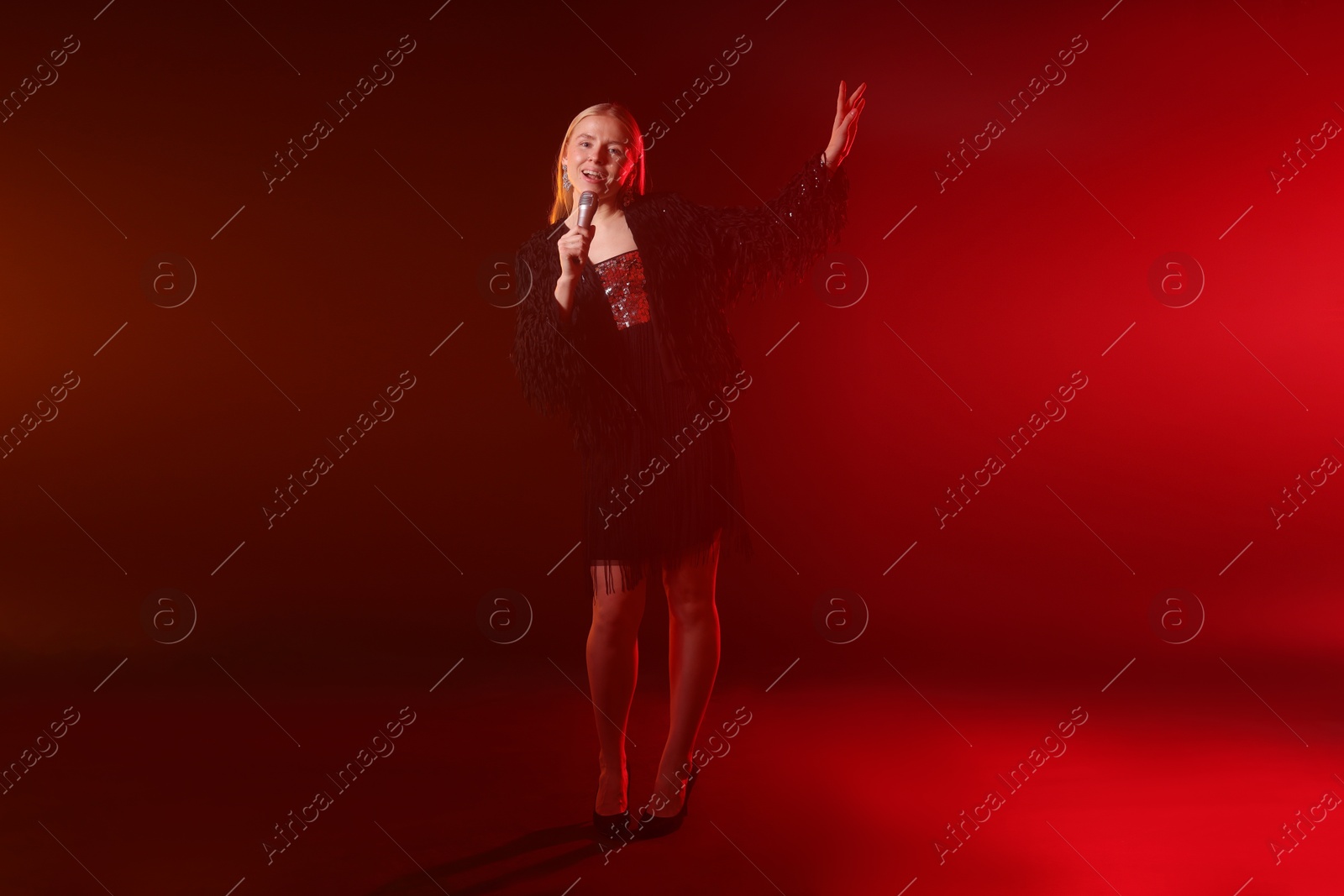 Photo of Beautiful singer performing on dark background with red light