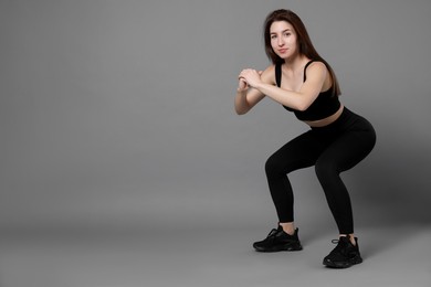 Photo of Woman in sportswear exercising on grey background, space for text