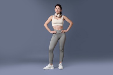 Photo of Woman in sportswear with headphones on grey background