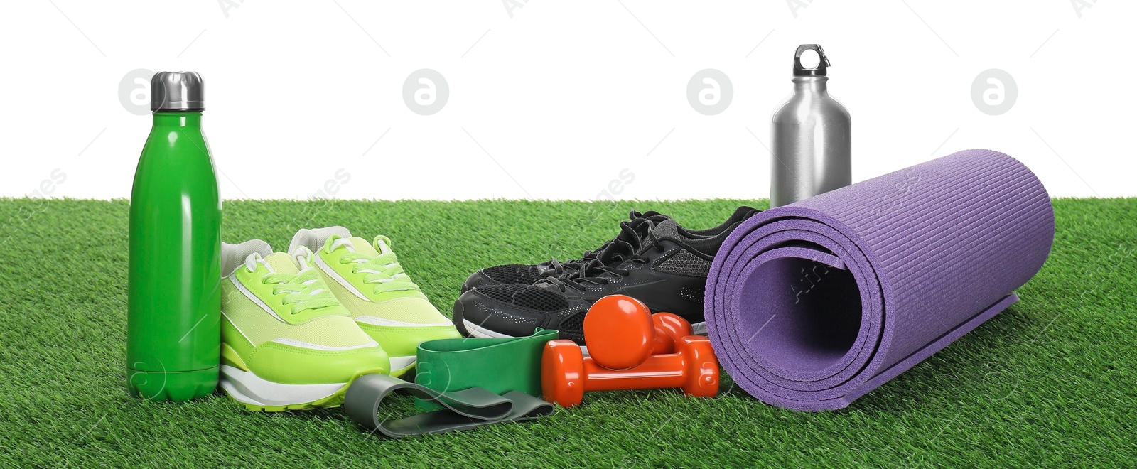 Photo of Different sport equipment on green grass against white background