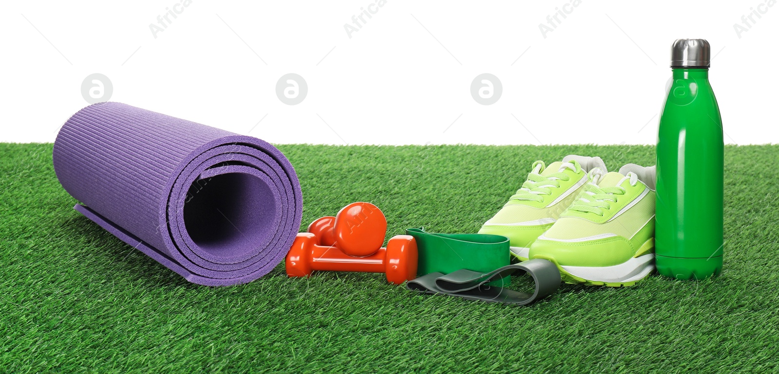 Photo of Different sport equipment on green grass against white background