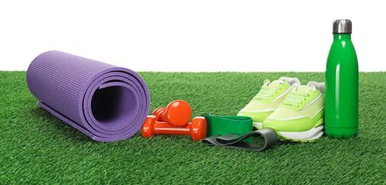 Photo of Different sport equipment on green grass against white background